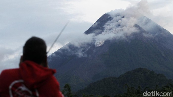 Warga mengamati Gunung Merapi yang mengeluarkan awan panas di Wonorejo, Hargobinangun, Pakem, Sleman, D.I Yogyakarta, Senin (18/1/2021). BPPTKG D.I Yogyakarta mencatat pada periode pengamatan Senin (18/1) pukul 00:00-06:00 WIB secara visual, Gunung Merapi mengeluarkan awan panas sebanyak satu kali dengan jarak luncur 1.000 meter, tinggi kolom 50 meter ke Tenggara arah Barat Daya serta guguran lava pijar sebanyak enam kali dengan jarak luncur maksimum 600 meter ke Barat Daya.