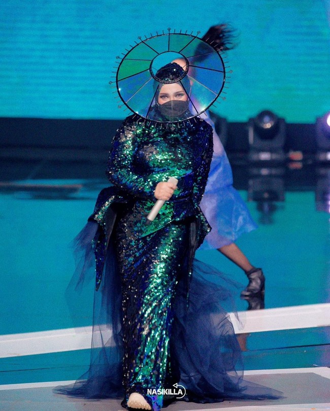 Dalam tampilan berikut, Melly Goeslaw mengenakan gaun dengan headpiece yang seolah bisa berfungsi sebagai faceshield. Headpiece karya Rinaldy Yunardi itu pun melengkapi penampilannya. Foto: Instagram @melly_goeslaw