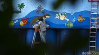 Seniman menyelesaikan pembuatan mural di dinding turap Sungai Ciliwung, Jakarta.