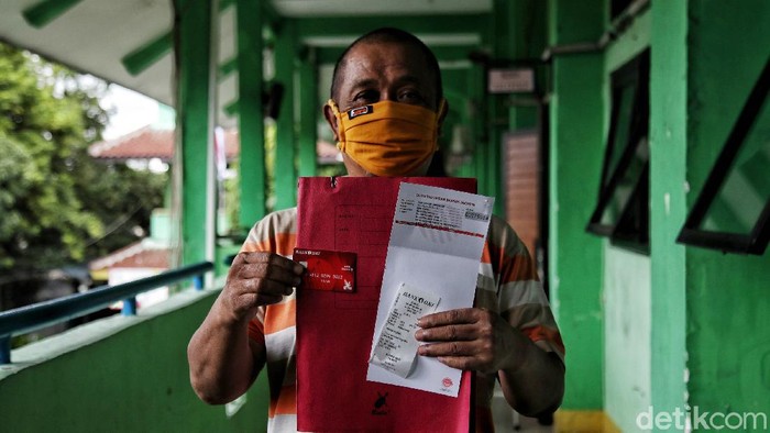 Penyaluran BST Pemprov DKI Jakarta Petugas Bank DKI Jakarta melayani warga untuk pemberian Bantuan Sosial Tunai Pemprov DKI Jakarta dengan dibuatkan buku tabungan bansos Jakarta di SMKN 12,Tanjung Priok, Jakarta Utara, Senin (18/1). Pemberian BST dengan nominal Rp. 300.000 per orang ini merupakan bantuan dari Pemprov DKI Jakarta untuk membantu warga yang terdampak pandemi COVID-19. Nantinya uang tersebut akan ditransfer ke rekening warga yang bersangkutan.