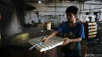 Seorang perajin melakukan pemotongan tahu sesuai ukuran yang telah ditentukan.