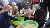 Tampak Menteri Sosial Tri Rismaharini (kedua kanan) didampingi Bupati Jember Faida (kedua kiri) membantu membungkus nasi saat mengunjungi Posko Banjir Desa Wonoasri di Tempurejo, Jember, Jawa Timur, Senin (18/1/2021).
