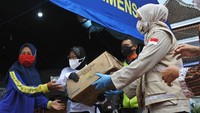 Menteri Sosial Tri Rismaharini (kedua kanan) didampingi Bupati Jember Faida (kanan) memberikan bantuan saat mengunjungi Posko Banjir Desa Wonoasri di Tempurejo, Jember, Jawa Timur, Senin (18/1/2021).
