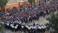 Para tentara yang mengenakan helm, membawa perisai anti huru-hara dan tongkat sempat membentuk barisan di sepanjang jalan utama di Chiquimula, Guatemala, untuk memblokir rombongan migran yang berupaya mencapai wilayah Amerika. AP Photo/Sandra Sebastian  