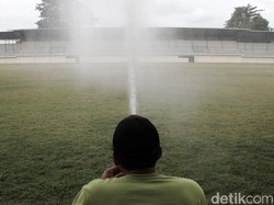 Petugas melakukan perawatan rumput dengan menyiram air.