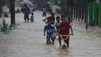Sejumlah bocah bermain sepeda di jalan yang tergenang banjir di Desa Kesambi, Mejobo, Kudus, Jawa Tengah, Selasa (19/1/2021). ANTARA FOTO/Yusuf Nugroho