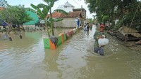 Warga berjalan menerobos banjir yang merendam Desa Suranenggala Lor, Kecamatan Suranenggala, Kabupaten Cirebon, Jawa Barat, Selasa (19/1/2021). ANTARA FOTO/Dedhez Anggara