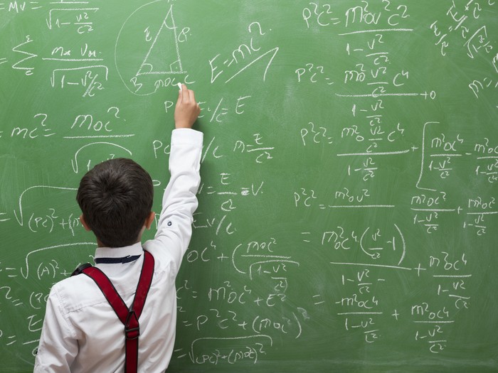 Little professor solving math problem on blackboard