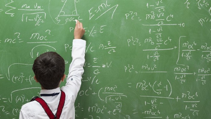 Little professor solving math problem on blackboard