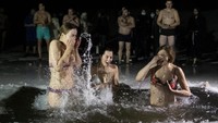 Walaupun suhu pada saat itu berkisar -26C, para jemaat tidak mengurungkan niatnya untuk terjun ke kolam dan sungai. AP Photo/Mindaugas Kulbis  