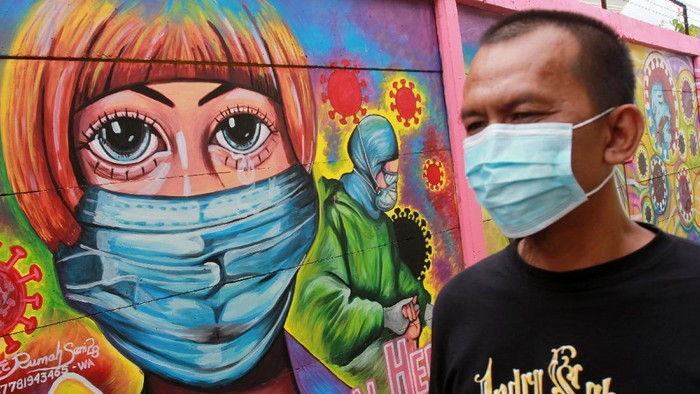 Warga melintas disamping mural yang bertemakan kampanye melawan COVID -19 yang ada di kawasan Tanah Tinggi, Tangerang, Banten, Rabu (20/1/2021). Kampanye dalam bentuk mural melawan COVID-19 tersebut merupakan bagian dari edukasi bagi masyarakat untuk lebih meningkatkan kewaspadaan terhadap pandemi itu. ANTARA FOTO/Muhammad Iqbal/foc.