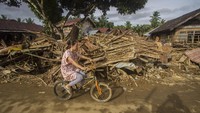 Warga menggunakan sepeda melintas di dekat puing-puing rumah akibat banjir bandang di Desa Waki, Kecamatan Batu Benawa,Kabupaten Hulu Sungai Tengah, Kalimantan Selatan, Rabu (20/1/2021).  ANTARA FOTO/BAYU PRATAMA S