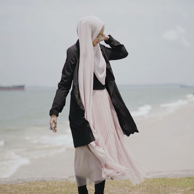 Wirda Mansur tetap menyempatkan diri liburan di sela-sela aktivitasnya. Liburan ke pantai, Wirda mengombinasikan luaran hitam dengan rok dan hijab warna pastel rose gold. Wirda memakai hijab segiempat yang menutupi bagian dada. Jika kamu ingin memakai gaya hijab ini, kamu harus memakai ninja, agar bisa menyematkan jarum pentul di bawah telinga dan menutupi bagian leher. Foto: Instagram @wirda_mansur
