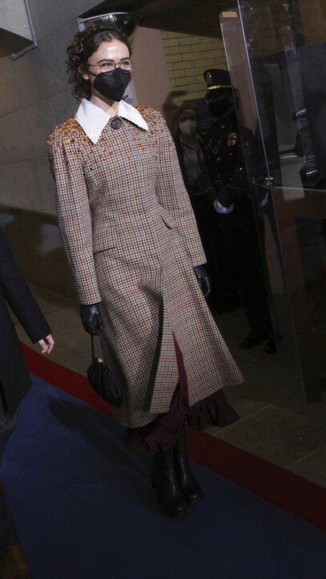 Anak tiri Kamala Harris, Ella Emhoff, pun ikut mencuri atensi berkat gaya preppy-edgy-nya dalam balutan coat Miu-Miu. Sejumlah majalah fashion menyertakan gaya Ella ini di daftar tamu inaugurasi dengan busana terbaik (Foto: AP/Win McNamee)