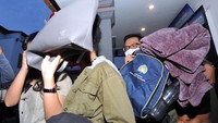 Sambil menutupi wajahnya dengan tas dan menghindari sorotan media, warga negara Amerika Serikat Kristen Antoinette Gray (kiri) dan rekannya Saundra Michelle Alexander (kanan) saat akan menuju ke Bandara Internasional I Gusti Ngurah Rai di Kantor Imigrasi Kelas I TPI Denpasar, Bali.