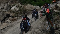 Anggota TNI membantu mengatur kendaraan di Jalan Trans Sulawesi Poros Majene-Mamuju yang terkena longsor di Majene, Sulawesi Barat, Rabu (20/1/2021). Jalur yang sempat terputus akibat longsor tersebut sudah bisa dilalui dengan sistem buka tutup arus kendaraan dari dua arah.