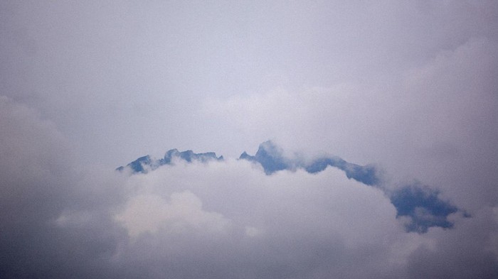 Gunung Raung tertutup awan terlihat dari Desa Garahan, Silo, Jember, Jawa Timur, Kamis (21/1/2021). Status Gunung Raung naik dari level I atau normal menjadi level II atau waspada karena mengalami erupsi kecil sejak Rabu (20/1). ANTARA FOTO/Seno/foc.