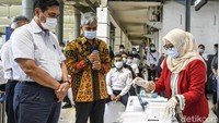 Menteri Koordinator Bidang Kemaritiman dan Investasi, Luhut Binsar Pandjaitan (kiri) didampingi Kepala Produksi Konsorsium GeNose C19 Eko Fajar Prasetyo (tengah) mengamati kantong nafas miliknya saat dites di Stasiun Pasar Senen, Jakarta, Sabtu (23/1/2021).