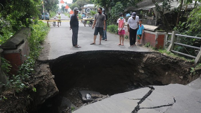 Warga mengamati jembatan rusak di Desa Gedangsewu, Kediri, Jawa Timur, Sabtu (23/1/2021). Jembatan yang menjadi akses utama antarkecamatan di wilayah tersebut ambrol karena tergerus derasnya aliran sungai Bening usai hujan deras. ANTARA FOTO/Prasetia Fauzani/aww.