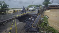 Pengendara sepeda motor melintas di Jembatan Sungai Salim yang opritnya terputus akibat banjir di Kecamatan Mataraman, Kabupaten Banjar, Kalimantan Selatan, Jumat (15/1/2021).