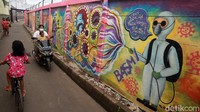 Warga melintas di depan mural bertema kampanye protokol kesehatan dan bahaya COVID-19, di Tanah Tinggi, Kota Tangerang, Sabtu (23/1/2021).