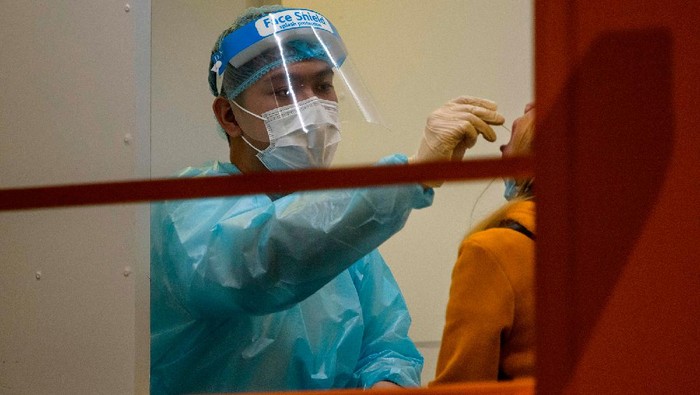 A resident (R) receives a mandatory Covid-19 coronavirus test by a health worker at a testing site in the Jordan area of the Yau Tsim Mong district of Kowloon in Hong Kong on January 22, 2021, an area of dense housing which has seen a recent spike in cases of the coronavirus. (Photo by Anthony WALLACE / AFP) (Photo by ANTHONY WALLACE/AFP via Getty Images)