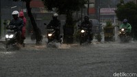 Pengendara nekat menerobos banjir menggunakan sepeda motornya