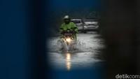 Pengendara sepeda motor nekat menerobos banjir di Perumahan Bumi Nasio Indah.