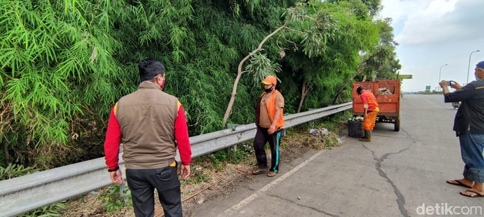 Bersih-bersih di pinggir jalan akses menuju Gerbang Tol Kalimalang 1, Bekasi, 25 Januari 2021. (Taufieq Renaldi Arfiansyah/detikcom)