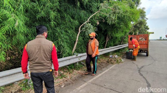 Bersih-bersih di pinggir jalan akses menuju Gerbang Tol Kalimalang 1, Bekasi, 25 Januari 2021. (Taufieq Renaldi Arfiansyah/detikcom)