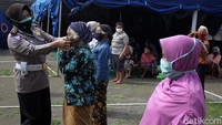Seorang Polwan memakaikan masker kepada seorang Lansia.
