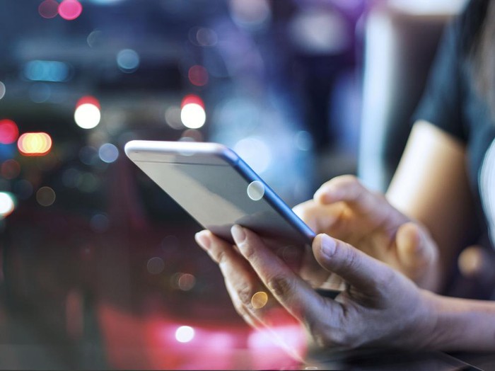 Woman using mobile smart phone in the night light colorful background