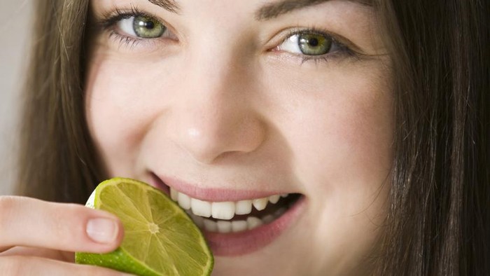 Female tasting a lime and smiling