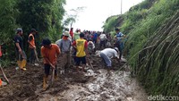 Warga bersama dan relawan membersihkan material tanah longsor yang menimbun jalan menuju Dukuh Songgobumi.