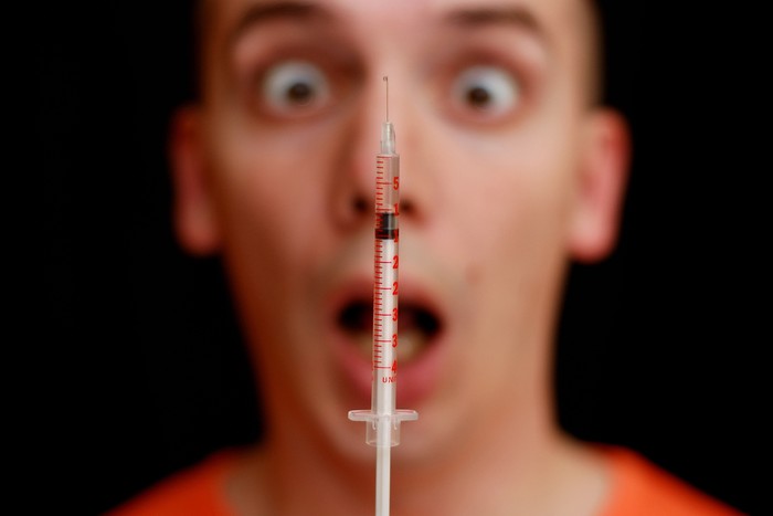 Frightened face of a man and a syringe - fear of injection.