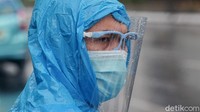 Seorang warga beraktivitas menggunakan jas hujan saat Jakarta diguyur hujan, Rabu (27/1/2021).