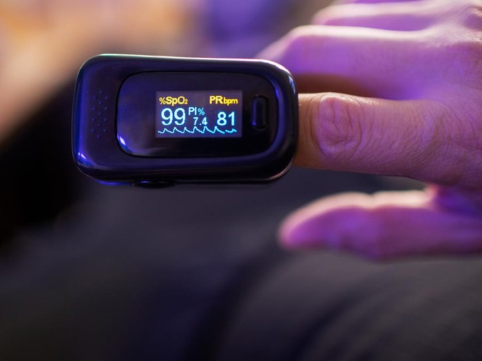 Woman hand introduced in a oximeter to check oxygen levels and pulse because Covid-19 pandemic