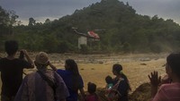 Sejumlah warga melihat helikopter Badan Nasional Penanggulangan Bencana (BNPB) saat tiba mengantarkan logistik bantuan korban banjir bandang di Desa Datar Ajab, Kabupaten Hulu Sungai Tengah, Kalimantan Selatan, Minggu (24/1/2021). 