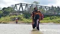 Warga menggendong anaknya saat menyeberangi sungai sepulang sekolah di wilayah pedalaman desa Panca, Kecamatan Lembah Seulawah, Kabupaten Aceh Besar, Aceh.