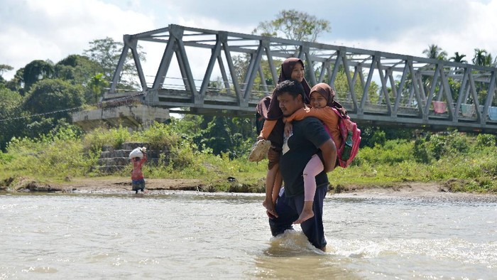 MURID SEKOLAH TERPAKSA MENYEBERANGI SUNGAI DI PEDESAAN ACEH Murid sekolah menumpang kendaraan warga saat menyeberangi sungai di wilayah pedalaman desa Panca, Kecamatan Lembah Seulawah, Kabupaten Aceh Besar, Aceh, Jumat, (22/1/2021). Menurut aparat desa, sejak tahun 2004 pascaputusnya jembatan gantung dan kemudian tahun 2008 dibangun jembatan kontruksi beton rangka baja yang hingga saat ini tidak tuntas pembangunannya, anak sekolah dan warga terpaksa menyeberangi sungai dan jika musim penghujan air sungai deras aktivitas belejar lumpuh dan begitu juga pemasaran komoditas pertanian ke ibukota provinsi Aceh terhenti karena tidak ada jalan alternatif lainnya. ANTARA FOTO/Ampelsa/hp.