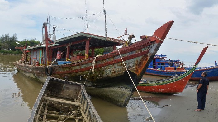 Petugas Pangkalan Pengawasan Sumber Daya Kelautan dan Perikanan (PSDKP) mengamankan satu unit kapal ikan pukat trawl (kiri) pascapenangkapan,  di dermaga Lampulo, Banda Aceh, Aceh, Kamis (28/1/2021). Kapal nelayan lokal, KM Baroena dengan bobot 30 GT itu ditangkap di perairan Aceh Utara dan mengamankan tujuh ABK-nya serta alat tangkap pukat trawl setelah mendapat laporan dari nelayan setempat maraknya terjadi praktek illegal fishing  di perairan Aceh Utara dan perairan Aceh  Timur, provinsi Aceh. ANTARA FOTO/Ampelsa/hp.