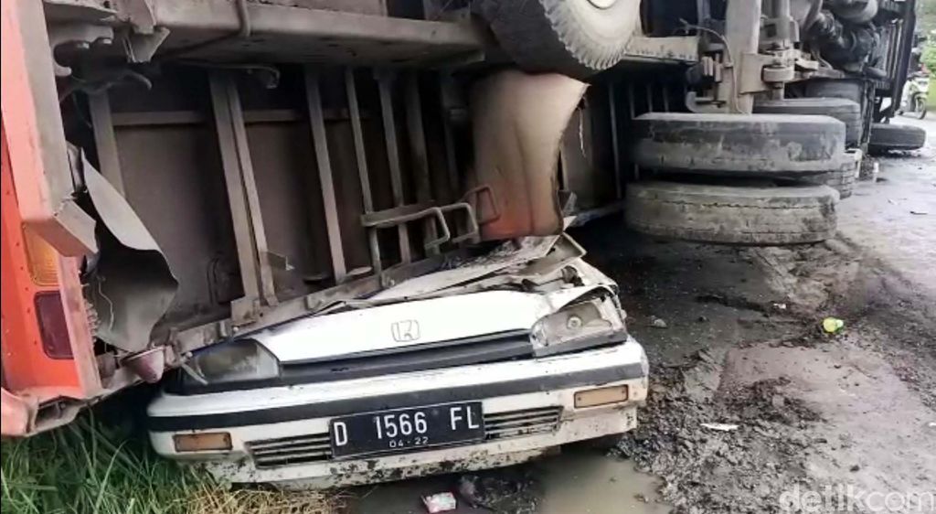 Truk pengangkut air minuman dalam kemasan terguling menimpa mobil di Jalan Raya Bogor - Sukabumi. Mobil yang tengah diparkir itu pun ringsek.