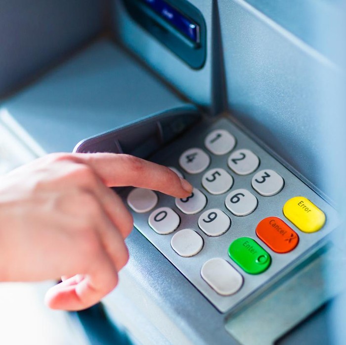 Close-up of hand entering PIN/pass code for a money transfer, on a ATM/bank machine keypad outside