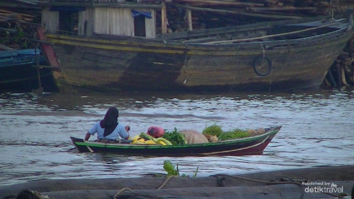 Pedagang membawa hasil bumi berupa sayur dan buah menggunakan jukung