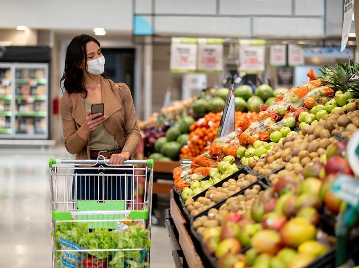 1218500870 Woman wearing protective mask preparing for virus pandemic spread quarantine.Hygiene, cleaning and disinfection products.Preventive measures and protection.Supply shopping during the epidemic.