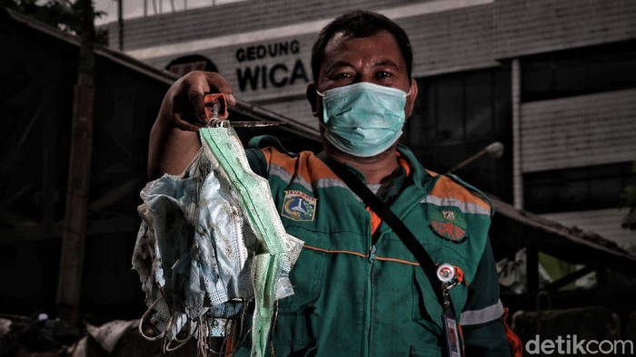 Petugas Suku Dinas Lingkungan Hidup mengambil limbah medis berupa masker di kawasan Dipo Ancol, Jakarta Utara, Senin (1/2). Dinas Lingkungan Hidup DKI Jakarta mengumumkan data limbah medis infeksius selama pandemi COVID-19 pada 2020. Berdasarkan data mereka, berat limbah medis ini yakni menembus 12.785 ton.
