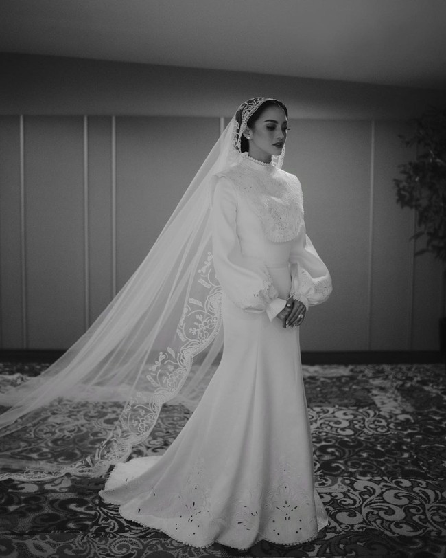 Di hari pernikahannya, Ririn Ekawati tampil mempesona dengan balutan gaun pengantin bernuansa vintage rancangan Hian Tjen. Gaun terbuat dari sutra duccess berwarna off-white yang dihiasi detail bergaya klasik. Foto: Rio Motret via Insatagram @hiantjen