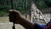 Warga memegang kawat penyanggah saat melintasi jembatan rawayan yang rusak di Desa Simpang, Cibalong, Kabupaten Garut, Jawa Barat, Minggu (31/1/2021).