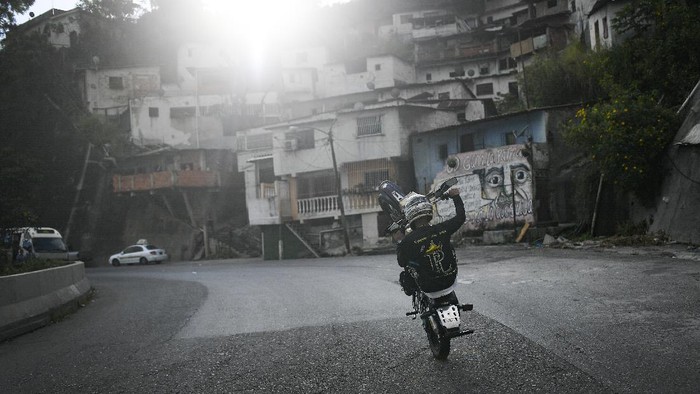 Motorcycle stuntman Pedro Aldana performs a wheelie on his motorbike as he rides to an exhibition along the old highway from Caracas to La Guaira, Venezuela, Sunday, Jan. 10, 2021. Aldana, who prefers his show name “Crazy Pedro, dares to beat the odds and put on exhibitions of speed and agility with a crew of like-minded daredevils atop their motorcycles. (AP Photo/Matias Delacroix)