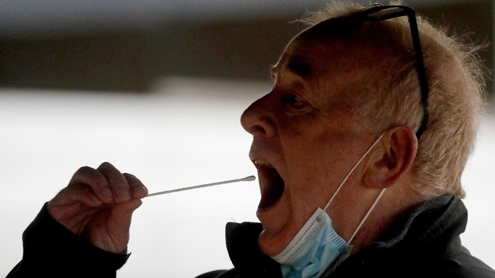 A man takes his own COVID-19 swab test at a newly set-up testing facility in a car park in West Ealing, London, Tuesday, Feb. 2, 2021. British health authorities plan to test tens of thousands of people in a handful of areas of England in an attempt to stop a new variant of the coronavirus first identified in South Africa spreading in the community. The Department of Health says a small number of people in England who had not travelled abroad have tested positive for the strain. (AP Photo/Frank Augstein)